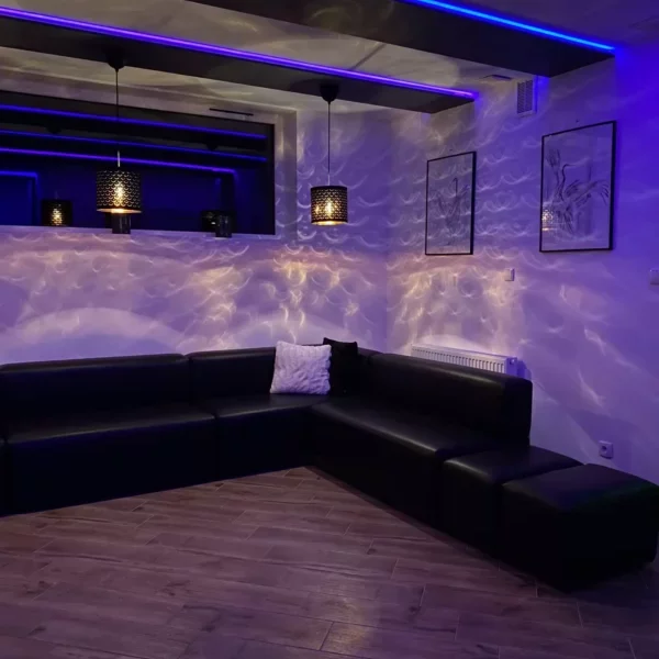 oświetlona sala z czarnymi pufami